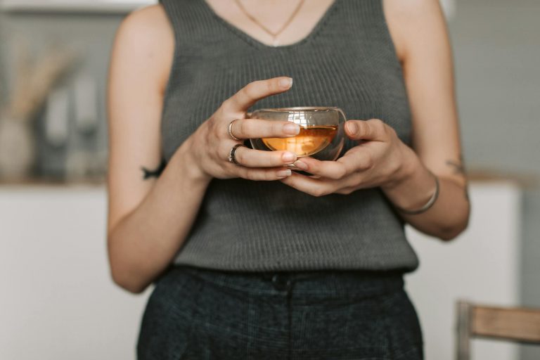 A person in a gray tank top enjoying a warm herbal tea indoors. Perfect serene lifestyle imagery.